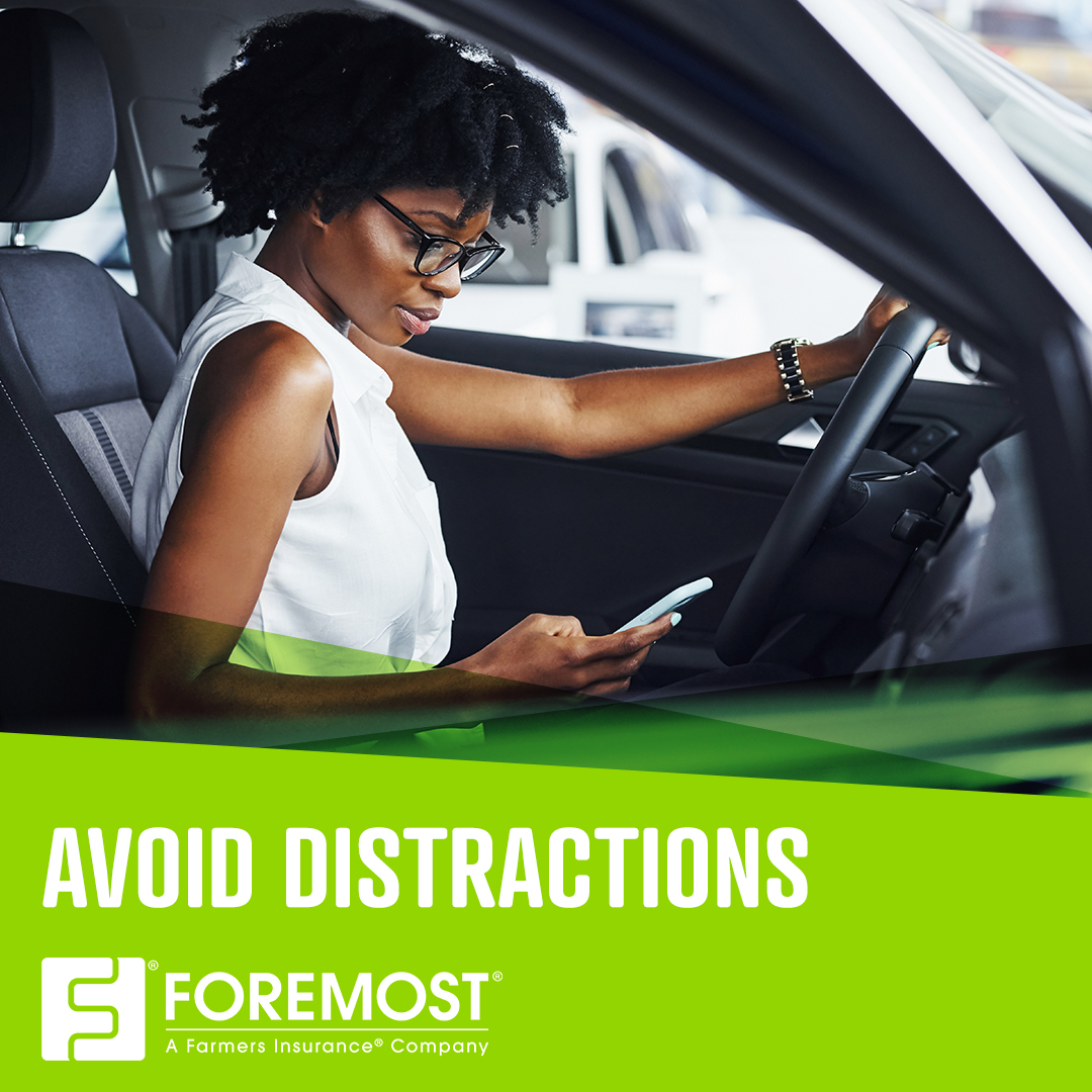 Woman driving with one hand on the wheel while looking down at cellphone